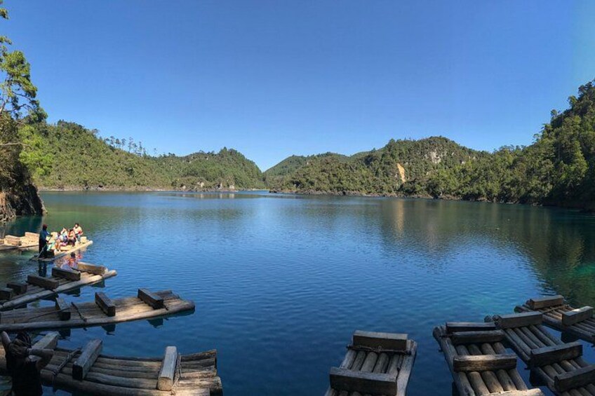 A calm lake with wooden docks and boats, surrounded by lush green hills. 1