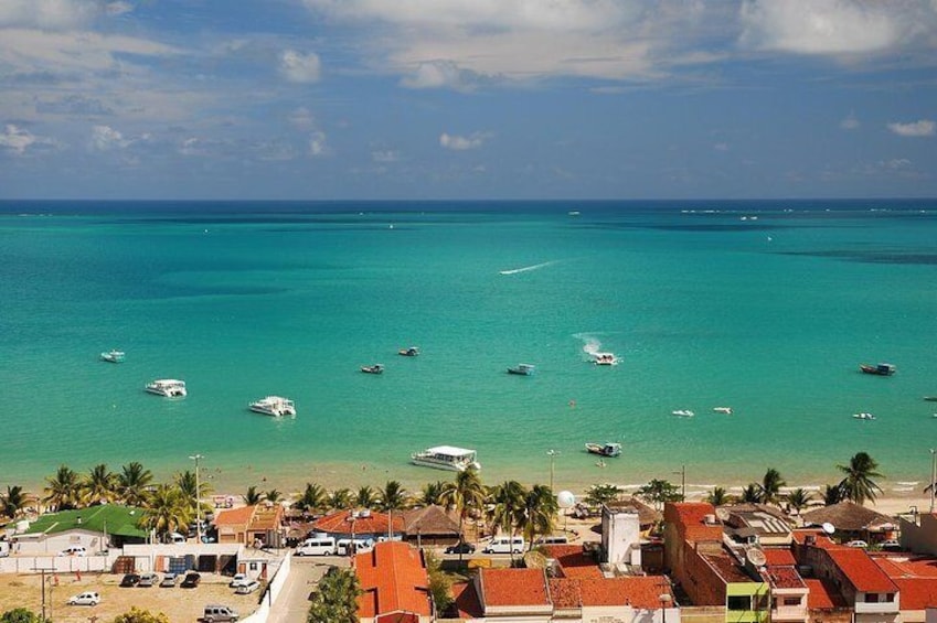 A coastal town with turquoise waters, boats, and palm trees. 1