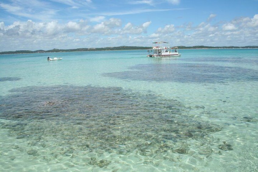 A clear turquoise sea with two boats, one closer to the shore and another further out. 3