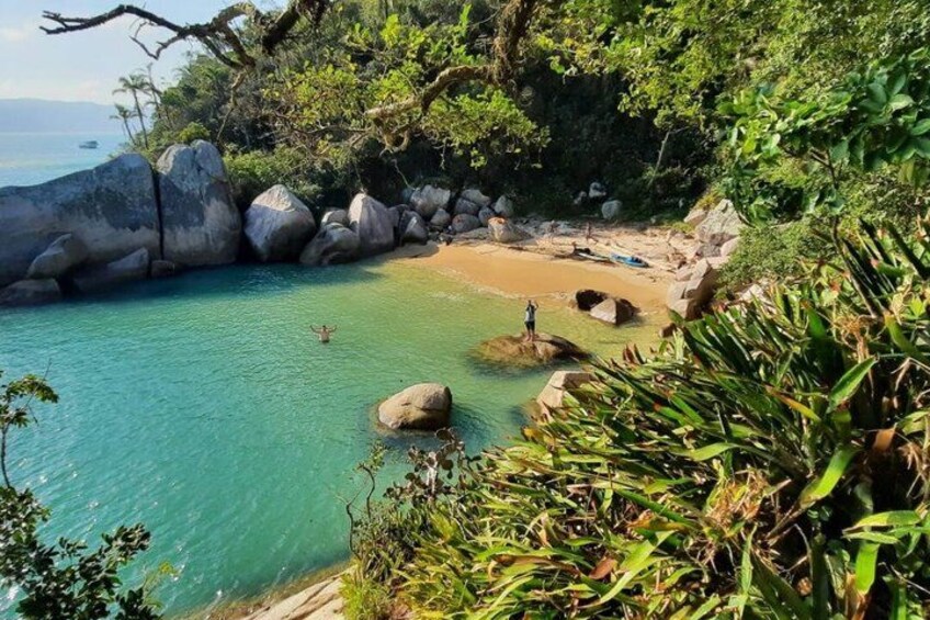 A coastal landscape with clear turquoise water, large rocks, and dense greenery. 2
