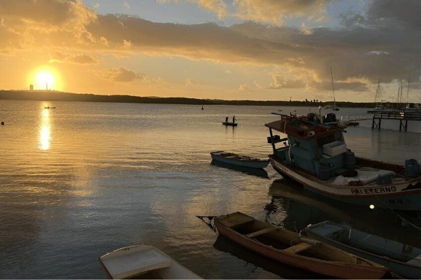 A calm harbor at sunset with boats docked, a clear sky, and a distant city skyline. 4