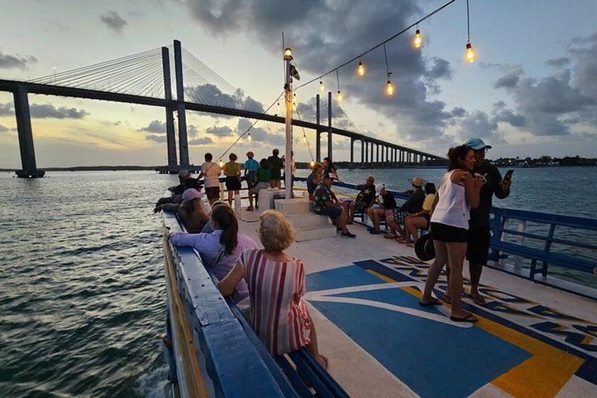 A bridge, people on a boat, and a sunset. 1