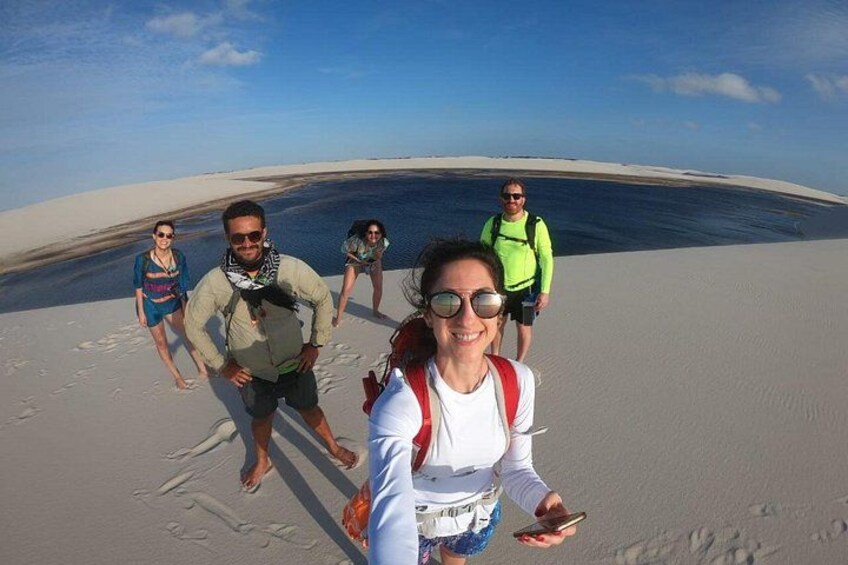 A group of people walking on a sandy beach with a large body of water in the background. 1