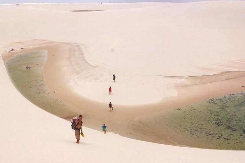 A large sand dune with people walking along its edge. 3