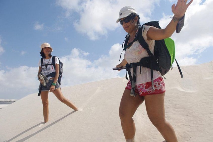 Two people hiking on a sandy slope with a clear sky. 2