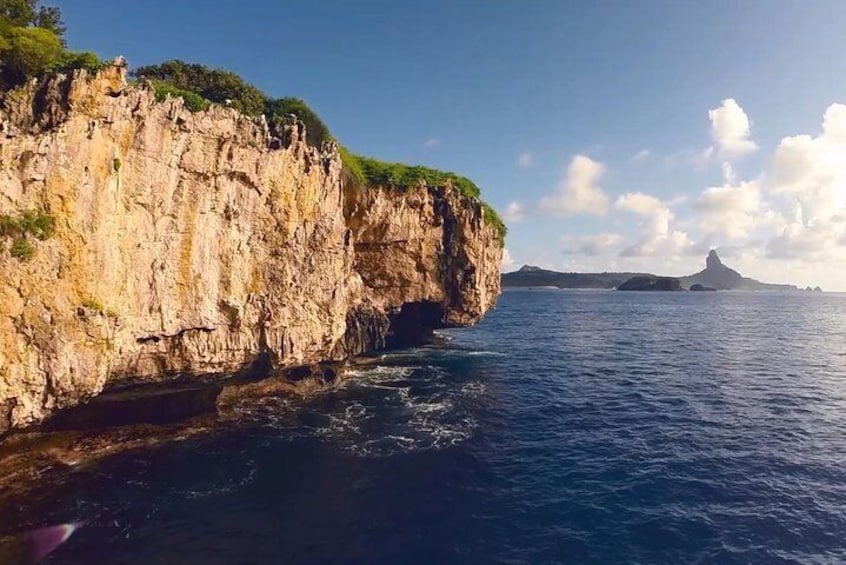A coastal cliff with a rocky shoreline and a distant island. 1