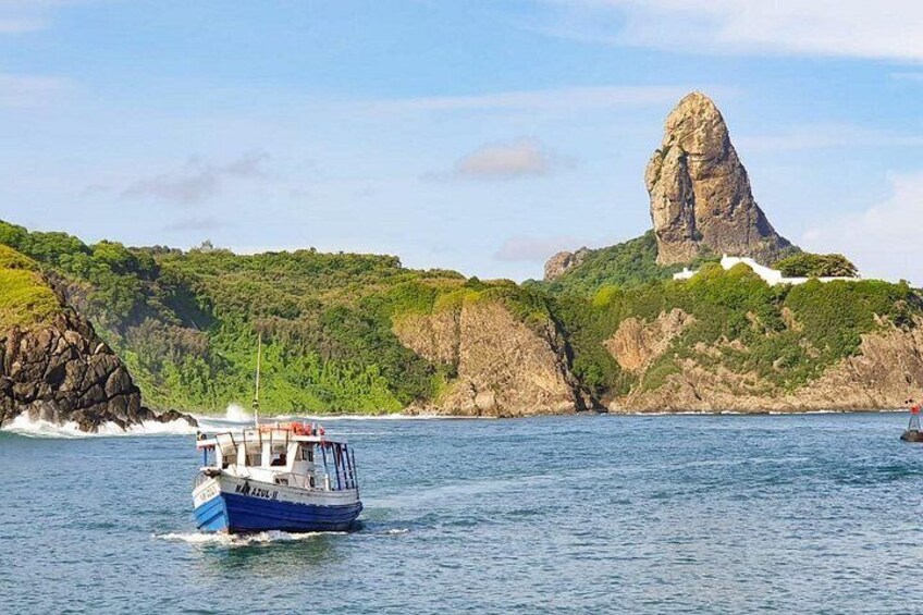 Un bateau sur une eau calme, une côte rocheuse et une formation rocheuse remarquable. 1