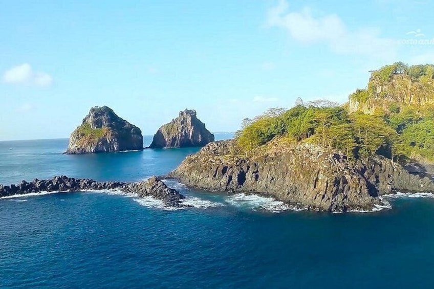 A coastal landscape with rocky outcrops and clear blue waters. 5