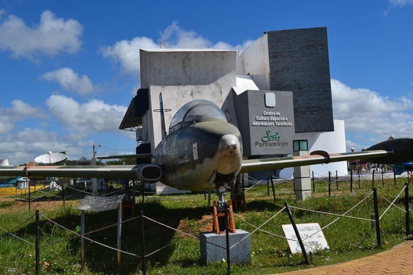 A vintage aircraft on display at a museum with a modern building in the background. 5