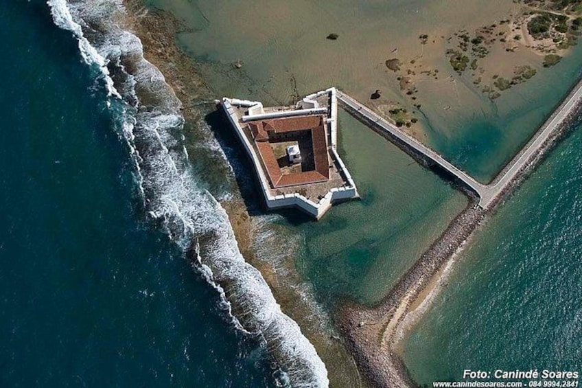 An aerial view of a coastal fortification with a surrounding moat and a connecting bridge. 2