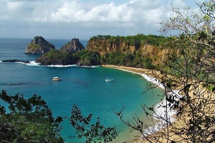 A coastal landscape with cliffs, a beach, and boats on the water. 2