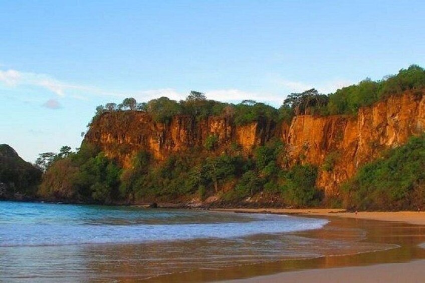 A coastal landscape with cliffs, a beach, and a calm sea. 4