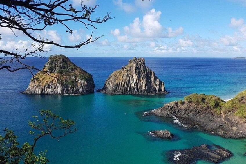 A coastal landscape with two prominent rock formations surrounded by turquoise waters. 5