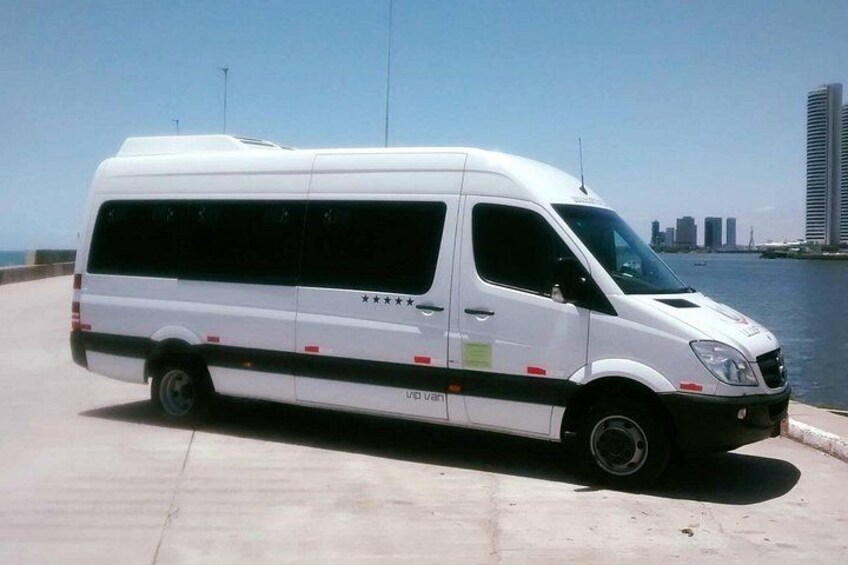 A white van parked by a waterfront with a city skyline in the background. 2