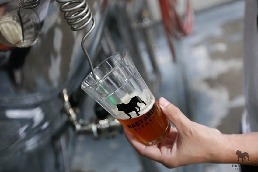 A hand holding a glass with a horse silhouette, a beer tap, and a tap handle. 2