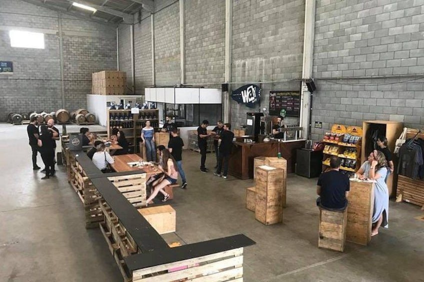 A warehouse with people interacting, wooden crates, and a counter with a sign. 2