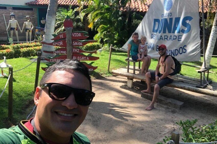 A man taking a selfie with a signpost in the background and a banner with the text "DUNIS DE MARAPE". 5