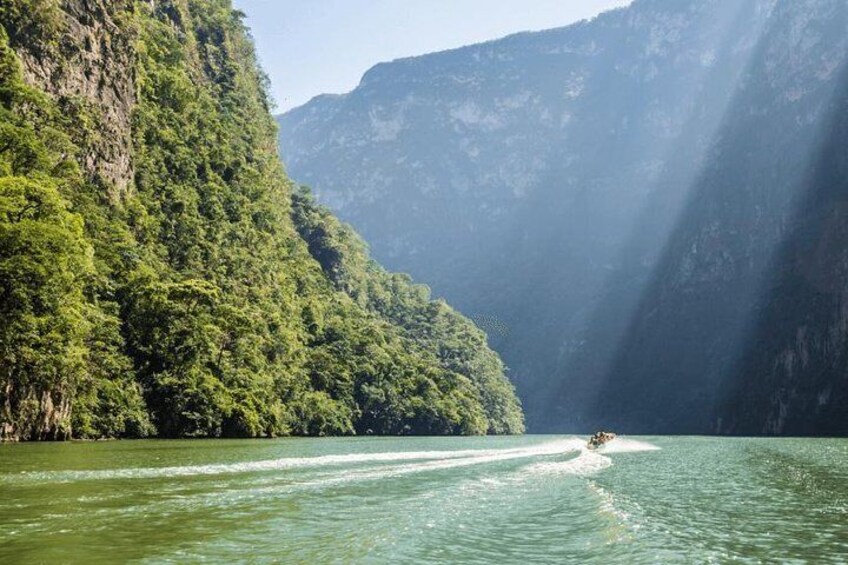 A boat on a river surrounded by lush green mountains. 5