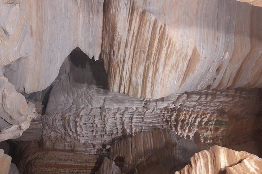 A rock formation with striations and a cave opening. 4