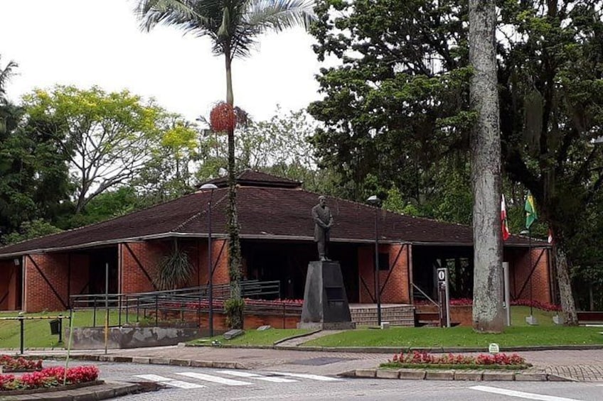 A building with a statue in front, surrounded by trees and flowers. 5