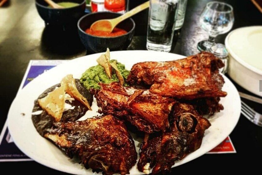 A plate of grilled meat with sides of guacamole and a red sauce. 4