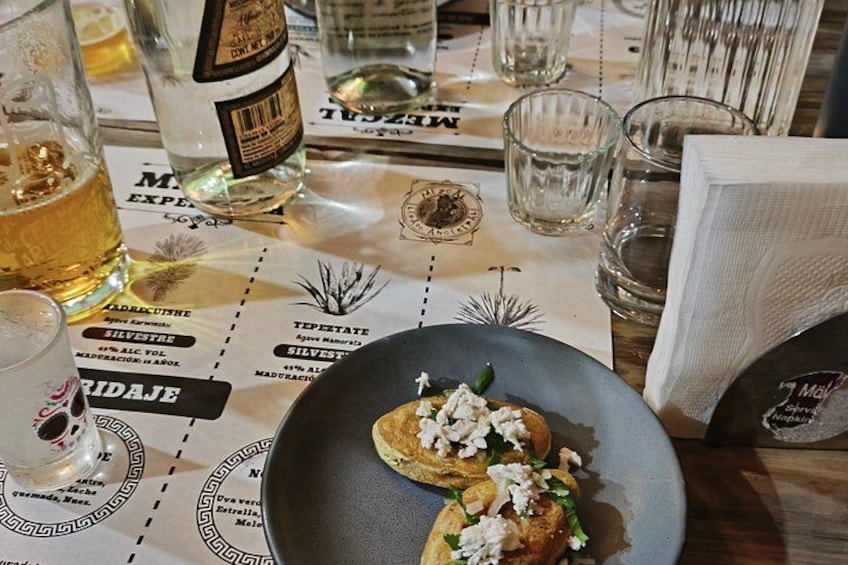 A table with a menu, a bottle of wine, glasses of beer, and a plate with food. 3