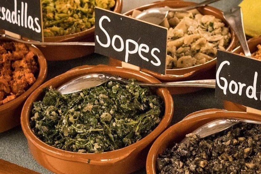 A variety of dishes in terracotta bowls with labels indicating names like 'Sopas,' 'Gordas,' and 'Sadasillas.' 5