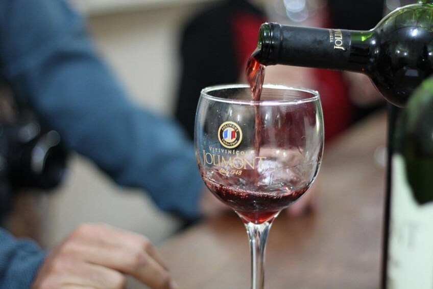 En flaska rött vin hälls upp i ett glas med en logotyp på. 5