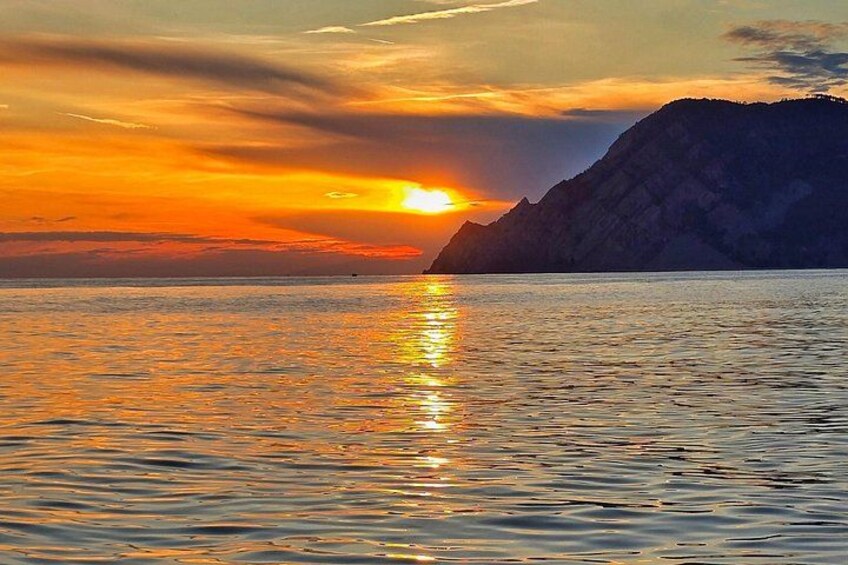 A sunset over a calm sea with a mountain silhouette. 2