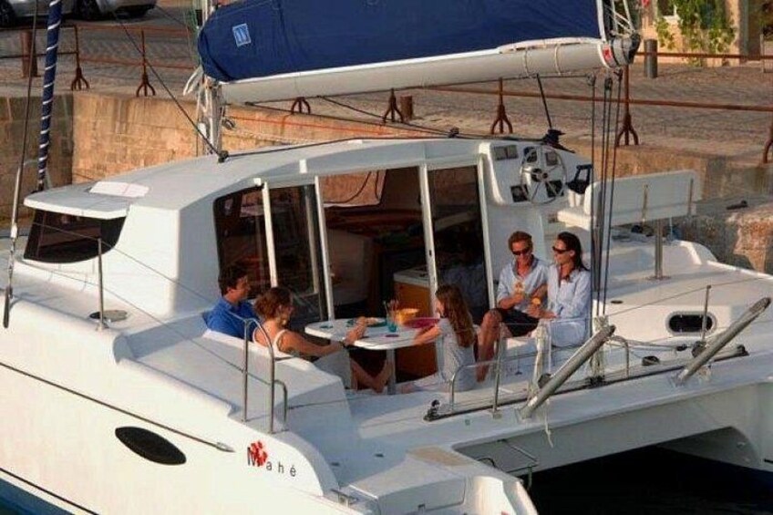 Un bote blanco con cubierta, personas sentadas en una mesa y un logotipo en el costado. 4