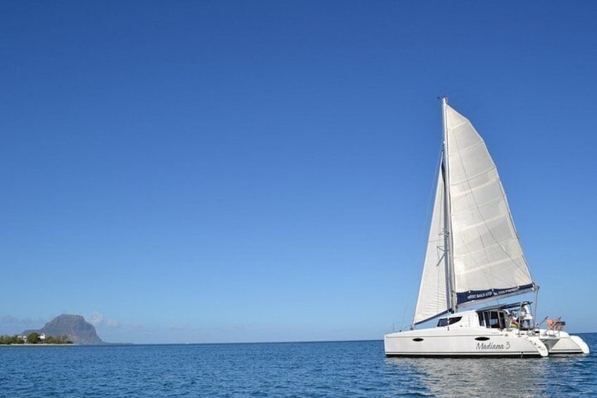 A sailboat named 'Manta' on calm waters with a clear sky and a distant island. 1