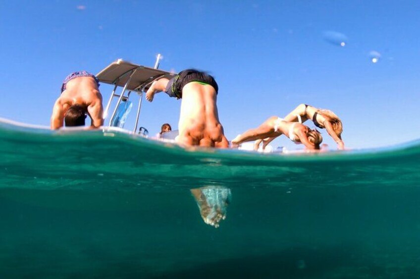 People swimming in the ocean, a boat, and clear blue water. 3