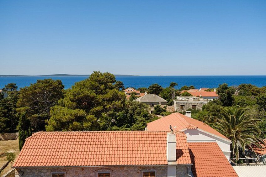 Eine Küstenstadt mit roten Dächern, einem wolkenlosen, blauen Himmel und Blick aufs Meer. 2