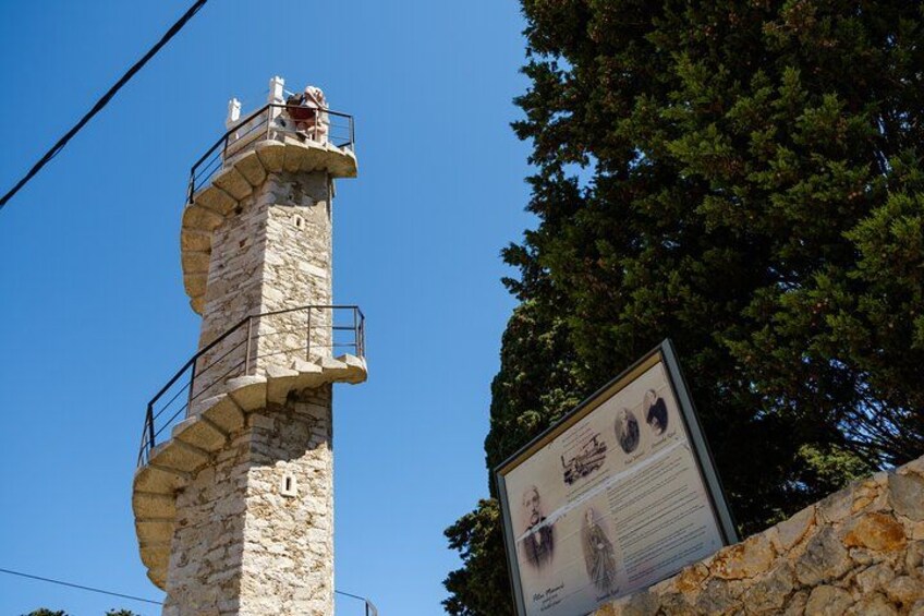 A stone tower with a spiral staircase, a plaque with historical information, and a clear blue sky. 5