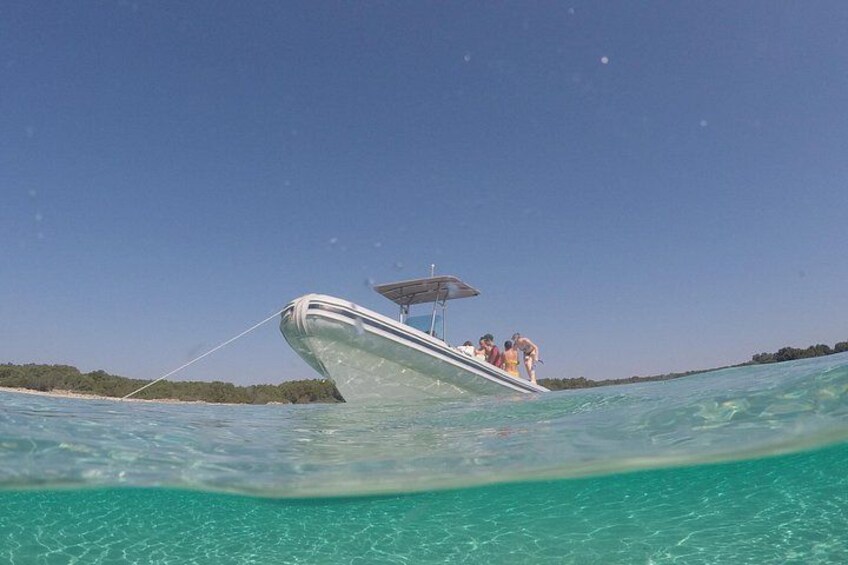 Ein Boot mit Personen an Bord, das auf klarem, türkisblauem Wasser treibt. 4