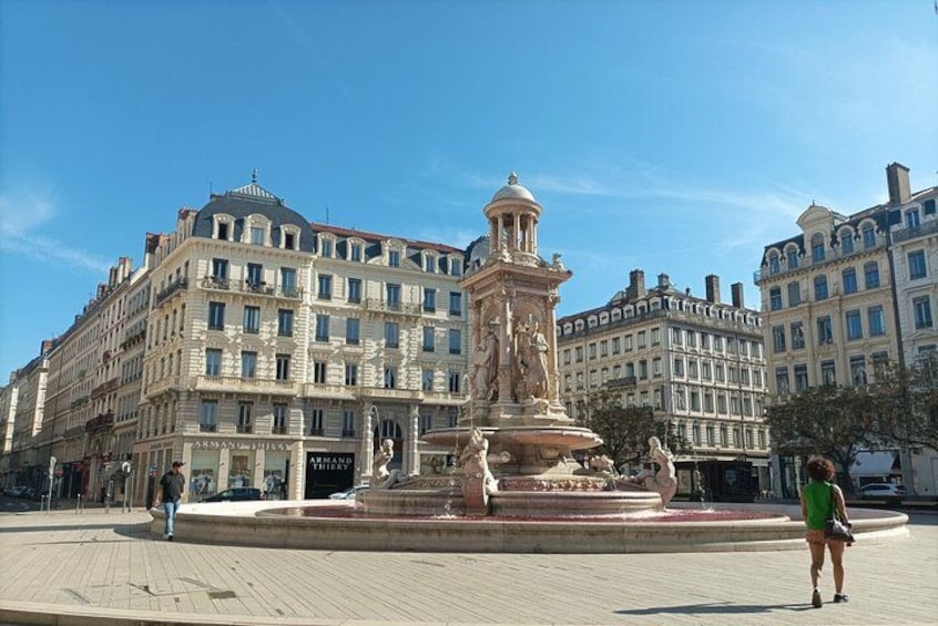 A square with a central fountain, surrounded by historic buildings with multiple stories and large windows. 2