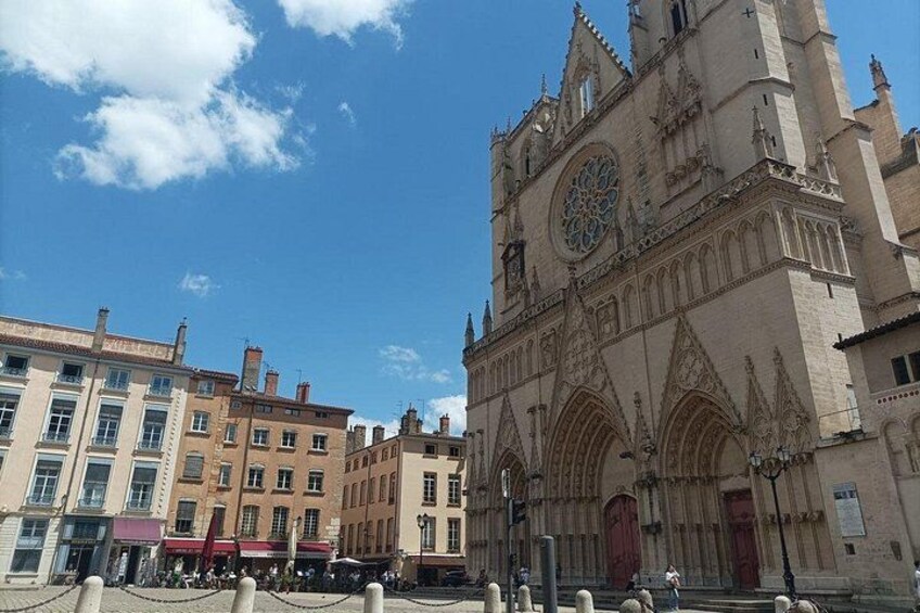 En historisk katedral med et stort tårn og et ur, omgivet af moderne bygninger. 1