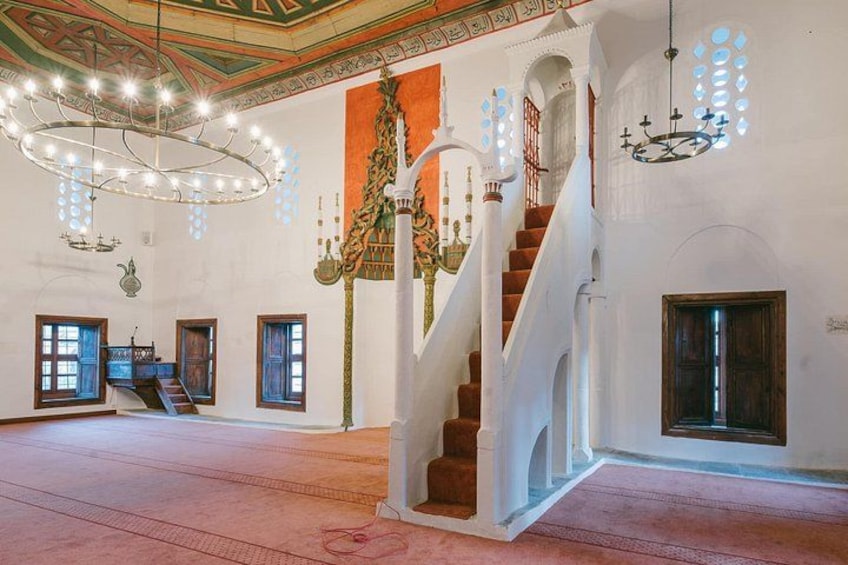 Un amplio salón con una imponente escalera, candelabros ornamentales y paredes con diseños. 5