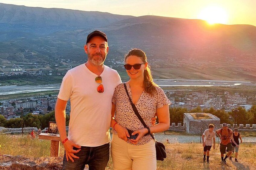 Una pareja está de pie en una colina, con vistas a un valle que tiene un río y edificios a lo lejos. 2
