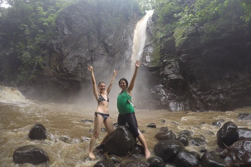 Twee personen staan in een rivier, met een waterval op de achtergrond. 2