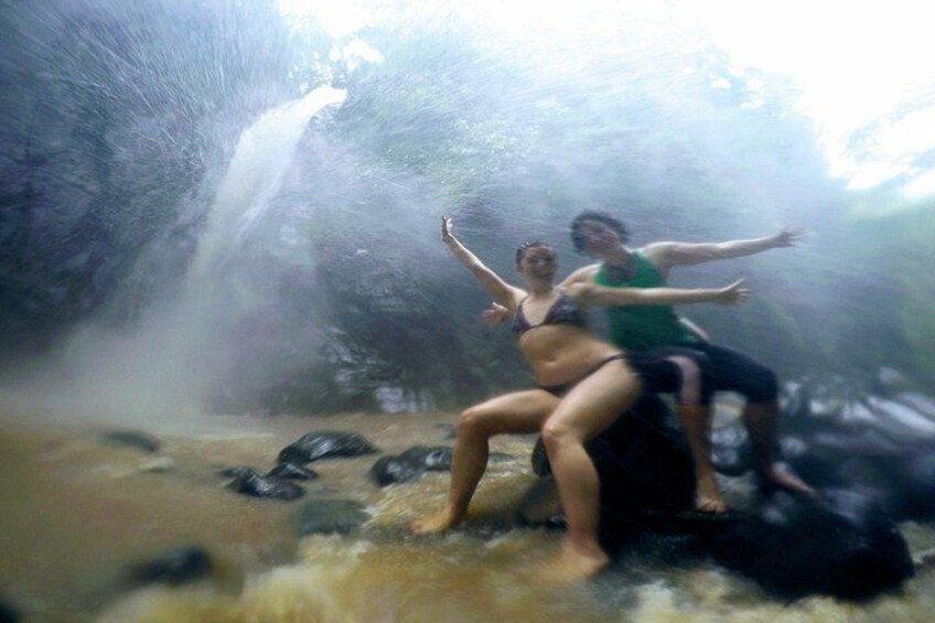 Twee personen zitten op een rots, met een waterval op de achtergrond. 3