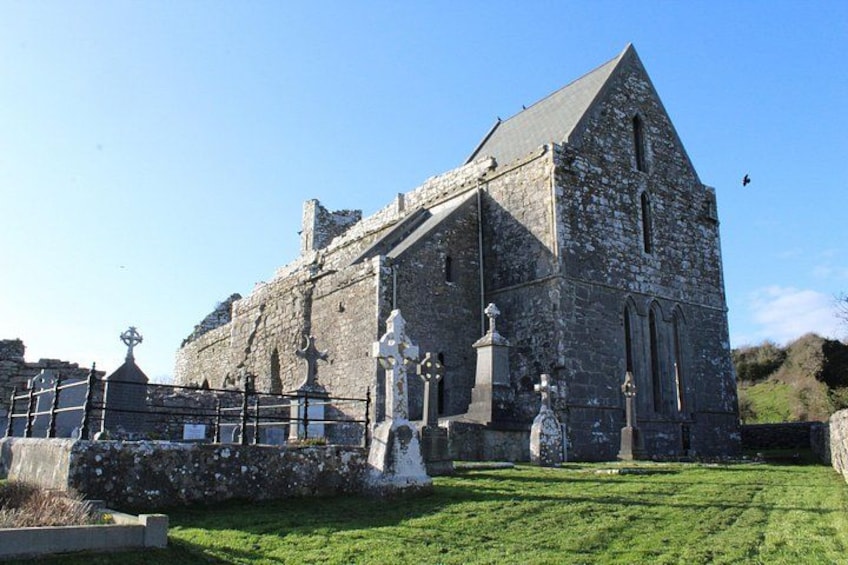 A stone church with a steep roof, a grassy lawn, and a stone fence. 5