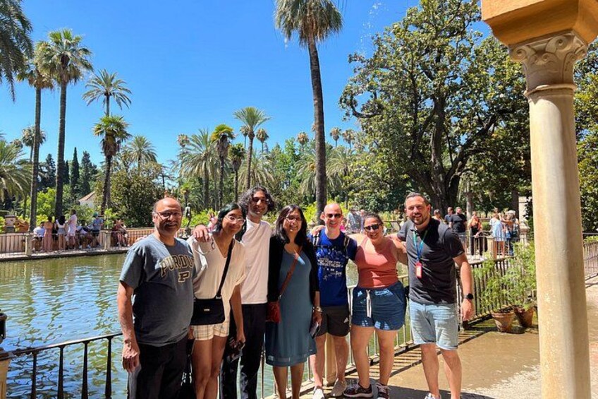 Un grupo de personas junto a un cuerpo de agua, con palmeras y un cielo despejado al fondo. 3