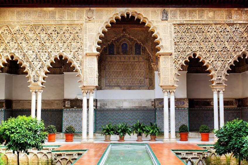 Une cour somptueuse, ornée d’arcades complexes, avec une piscine centrale et des plantes en pot. 1