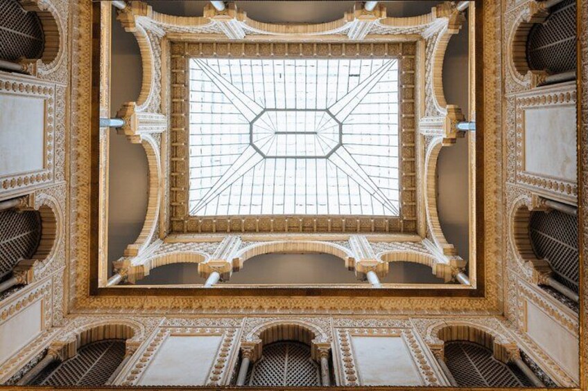 Un plafond richement décoré, orné de motifs géométriques et d’éléments architecturaux travaillés. 4