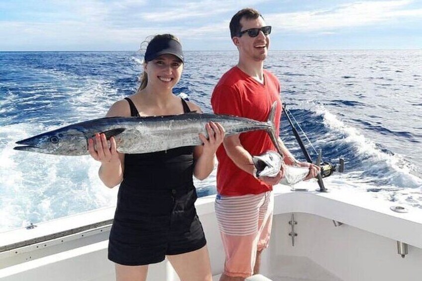 Two people on a boat holding fish. 1