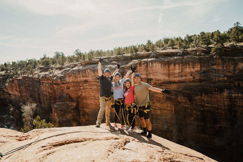 A group of people on a rock formation with a canyon in the background. 4