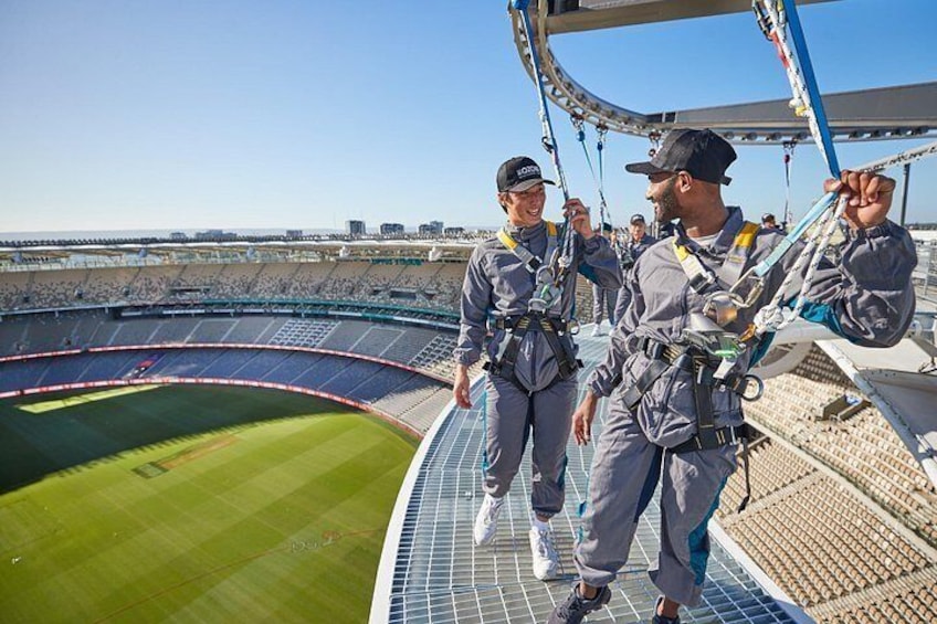 Un estadio con césped verde, personas con arneses de seguridad y un cielo despejado. 2