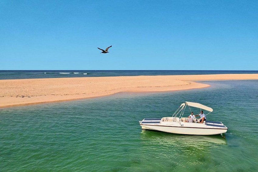 Un bote sobre aguas tranquilas, una playa arenosa y un cielo despejado. 4