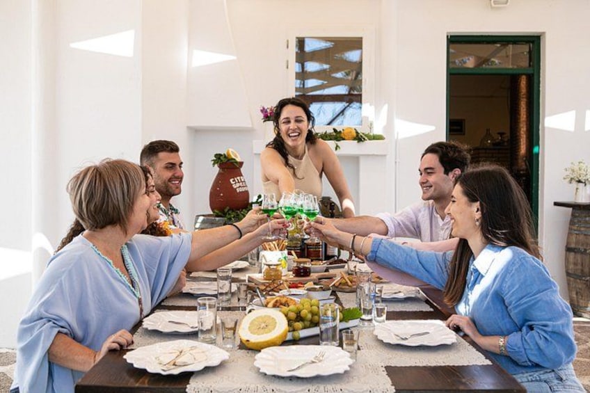 A group of people toasting at a table with a variety of food and drinks. 1